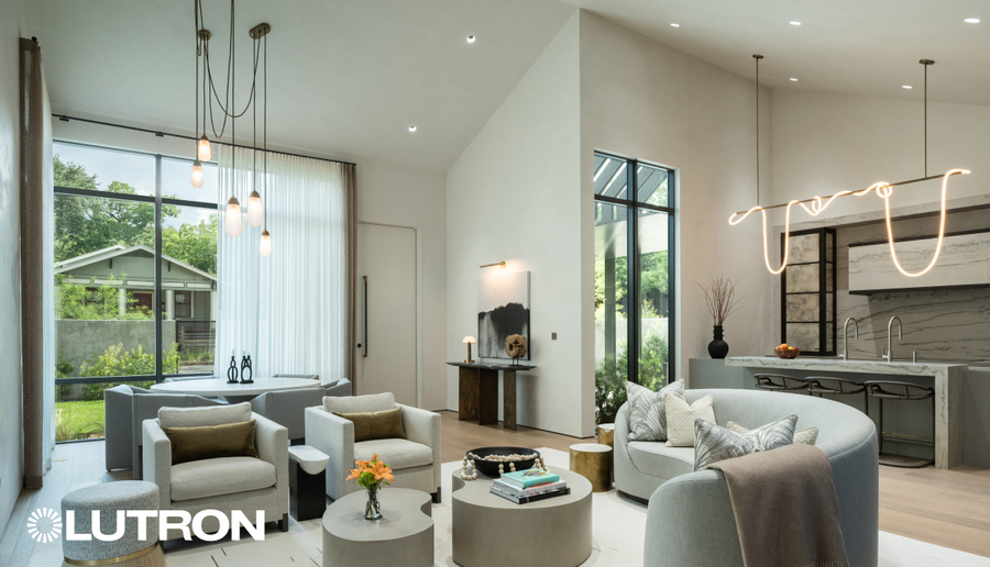 A view of a luxurious living, dining, and kitchen area with Lutron shades and lighting fixtures.