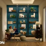 Cozy reading nook with modern lighting, a teal built-in bookshelf, and a person reading in a softly lit hallway.